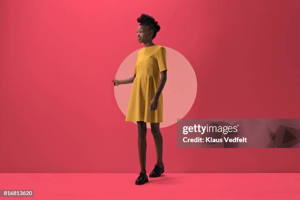 woman walking out from woman peeking out of round opening in coloured wall - woman fashion stock pictures, royalty-free photos & images