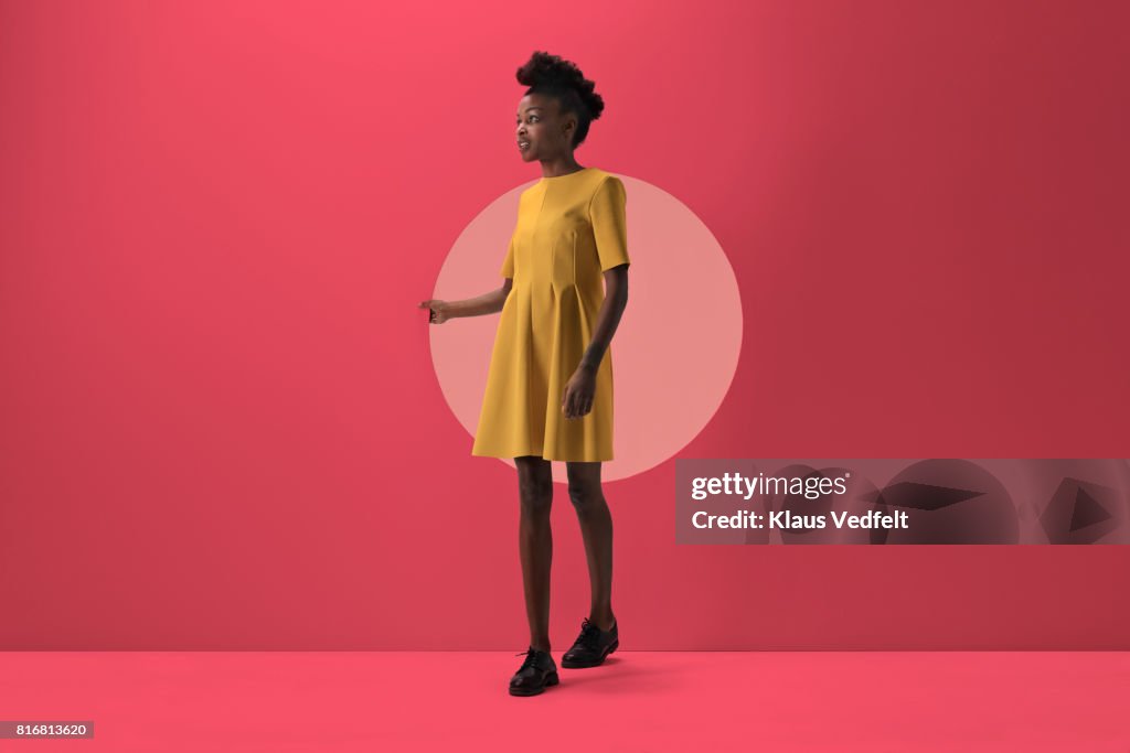 Woman walking out from Woman peeking out of round opening in coloured wall