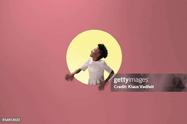 woman laughing, placed inside round opening in coloured wall - abstract color background stockfoto's en -beelden