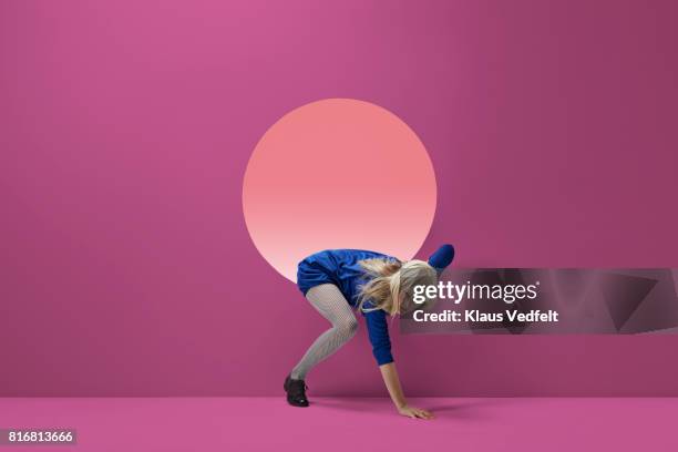 woman crawling out of round opening in coloured wall - crawl stock pictures, royalty-free photos & images