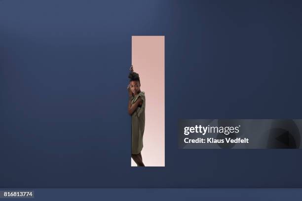 woman standing in rectangular opening of coloured wall - peeking stock pictures, royalty-free photos & images