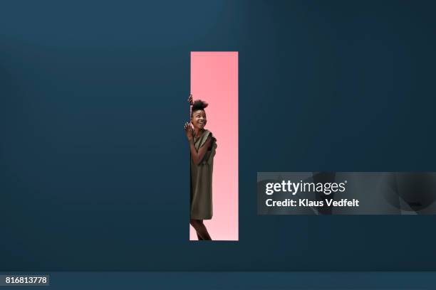 woman standing in rectangular opening of coloured wall - leunen stockfoto's en -beelden