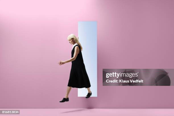 woman stepping threw rectangular opening of coloured wall - changing appearance photos et images de collection