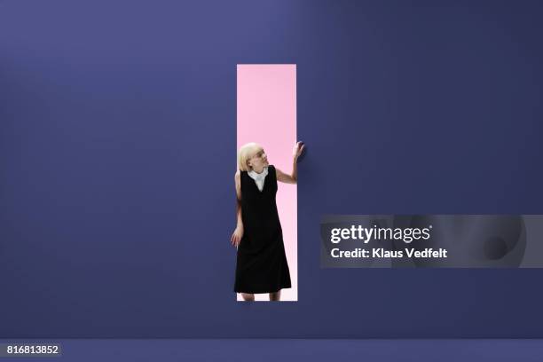 woman standing in rectangular opening of coloured wall - öresundregion stock-fotos und bilder