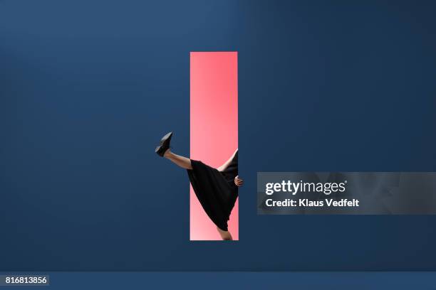 woman stepping threw rectangular opening of coloured wall - stappen stockfoto's en -beelden