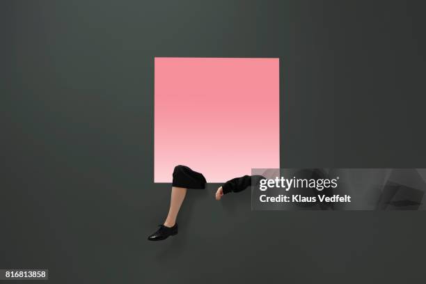 female arm and leg, dangling from square opening in coloured wall - female legs studio shot stock pictures, royalty-free photos & images