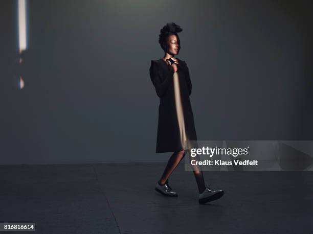 woman walking in thin light stripe, in studio with concrete floor - change appearance stock pictures, royalty-free photos & images