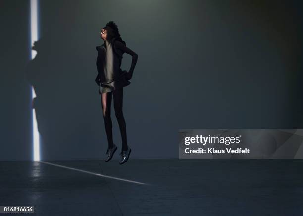 woman jumping in thin stripe og light, in studio with concrete floor - hovering fotografías e imágenes de stock