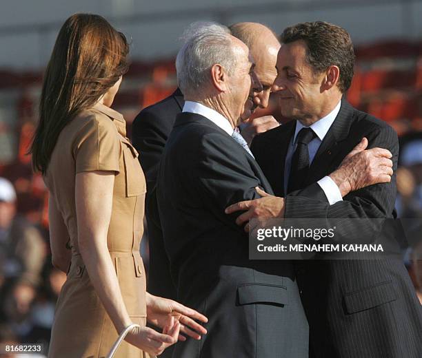 French First Lady Carla Bruni-Sarkozy stand as French President Nicolas Sarkozy hugs his Israeli counterpart Shimon Peres near Prime Minister Ehud...