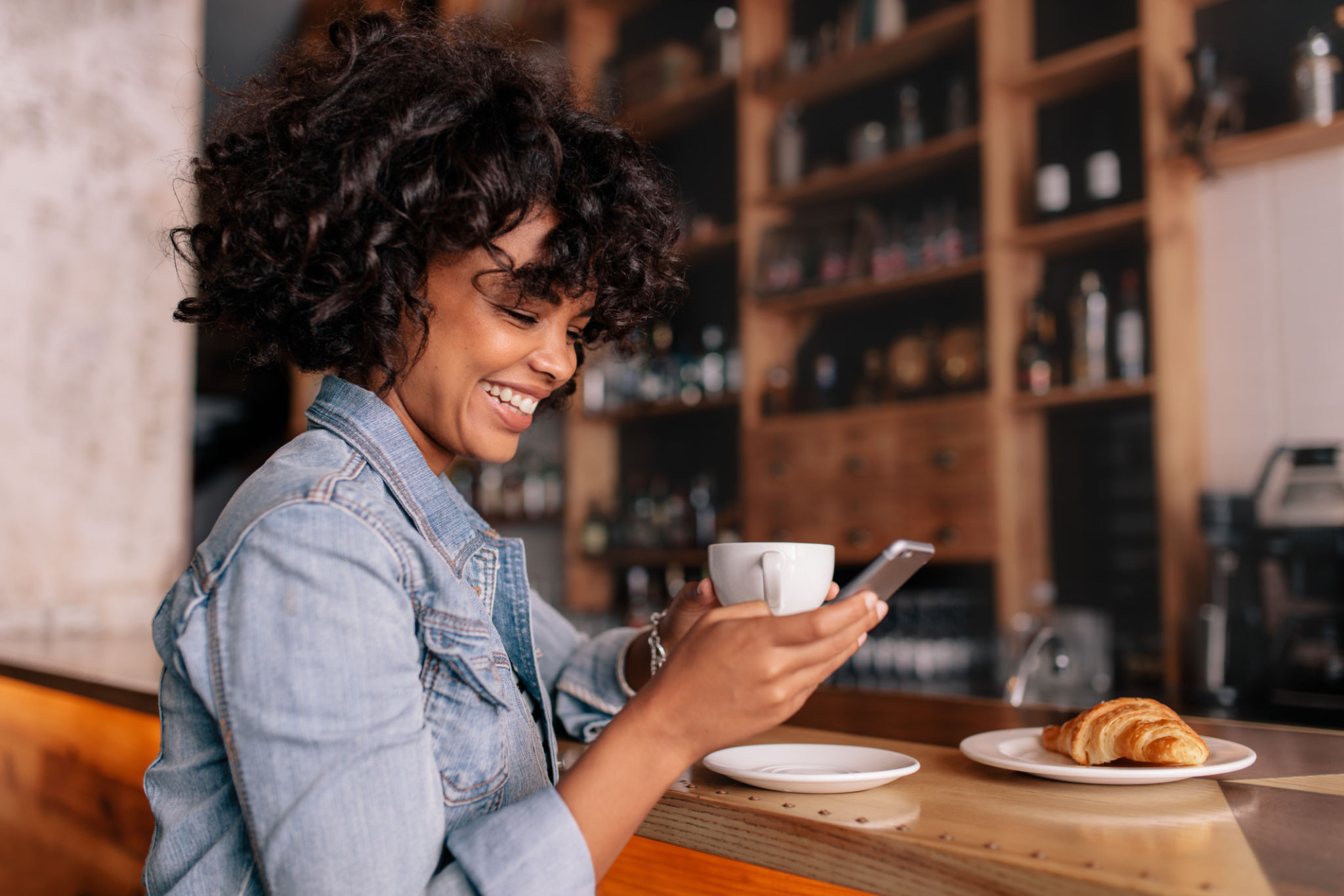 Smiling woman using smart phone in a modern cafe Smiling woman using smart phone in a modern cafe
