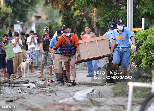 Policemen of the typhoon-hit Sibuyan island in central Philippines carry an improvised coffin bearing the body of a passenger from the sunken ferry...