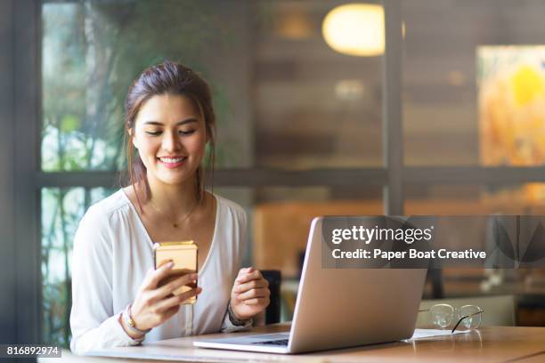 beautiful asian lady messaging her colleague, while working on some emails on her mac - philippines stock pictures, royalty-free photos & images