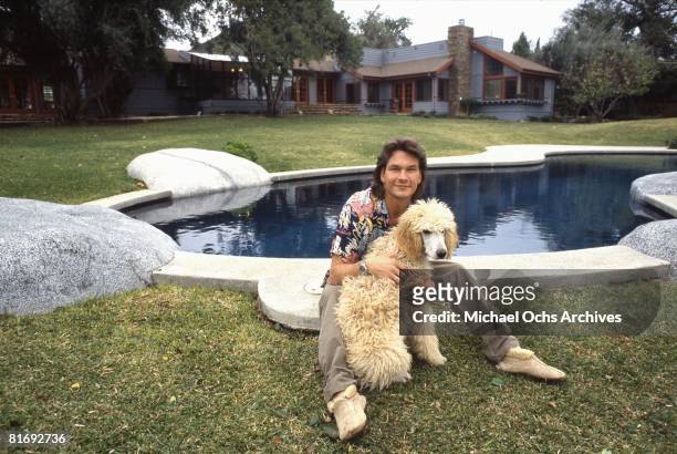 Actor and dancer Patrick Swayze poses for a portrait with his dog at home in 1987 in Los Angeles, California.