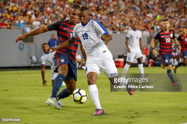 Daniel Herelle of Martinique gets past the defense of Juan Agudelo of the United States during the first half of the CONCACAF Group B match at...