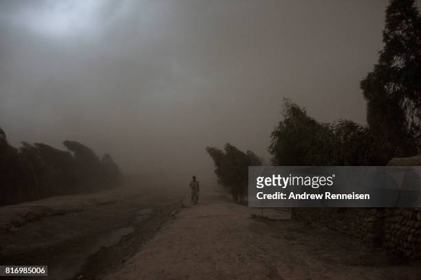 Anwar Pachir, whose family was displaced by the Islamic State of Iraq and Syria - Khorasan walks through a storm outside his current home on July 14...