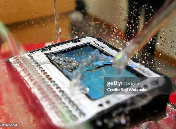 Model demonstrates the durability of Matsushita Co Ltd's new Panasonic notebook computer "Toughbook CF-U1" by pouring water on it at World Trade...