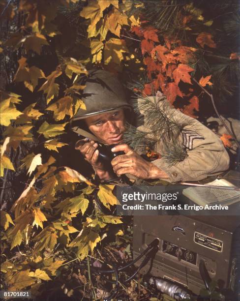 During a training exercise, an unidentified sergeant crouches under a tree and listens to the receiver of a Galvin BC-620A radio, Fort Belvoir,...