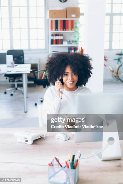 smiling female assistant using landline phone in modern office - landline phone home stock pictures, royalty-free photos & images