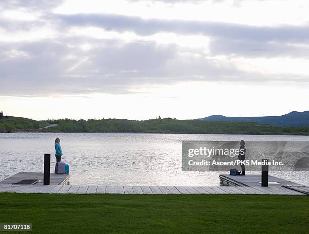 couple with luggage on opposing boat docks - standing apart stock pictures, royalty-free photos & images