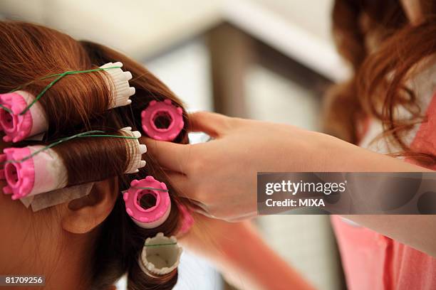 hairdresser putting curlers in customer's hair - permed hair stock pictures, royalty-free photos & images