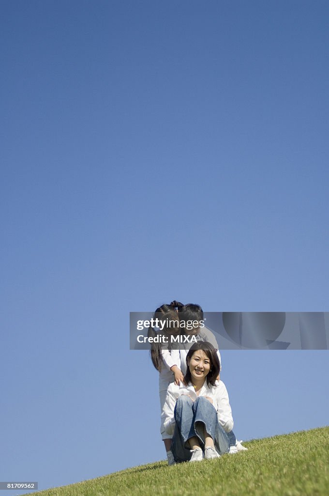 Mother and two children sitting in field