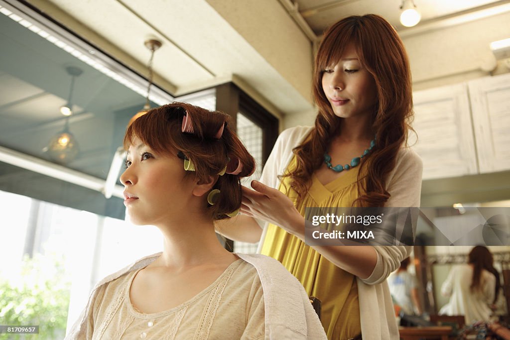 Hairdresser putting curlers in customer's hair