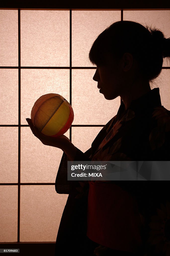 Silhouette of young woman holding paper balloon