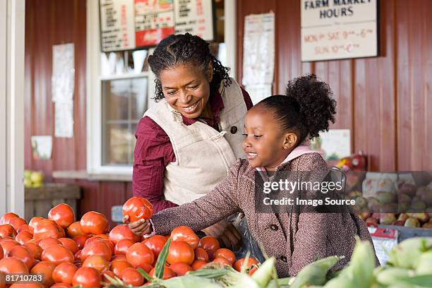 a grandmother and granddaughter choosing tomatoes - food market stockfoto's en -beelden