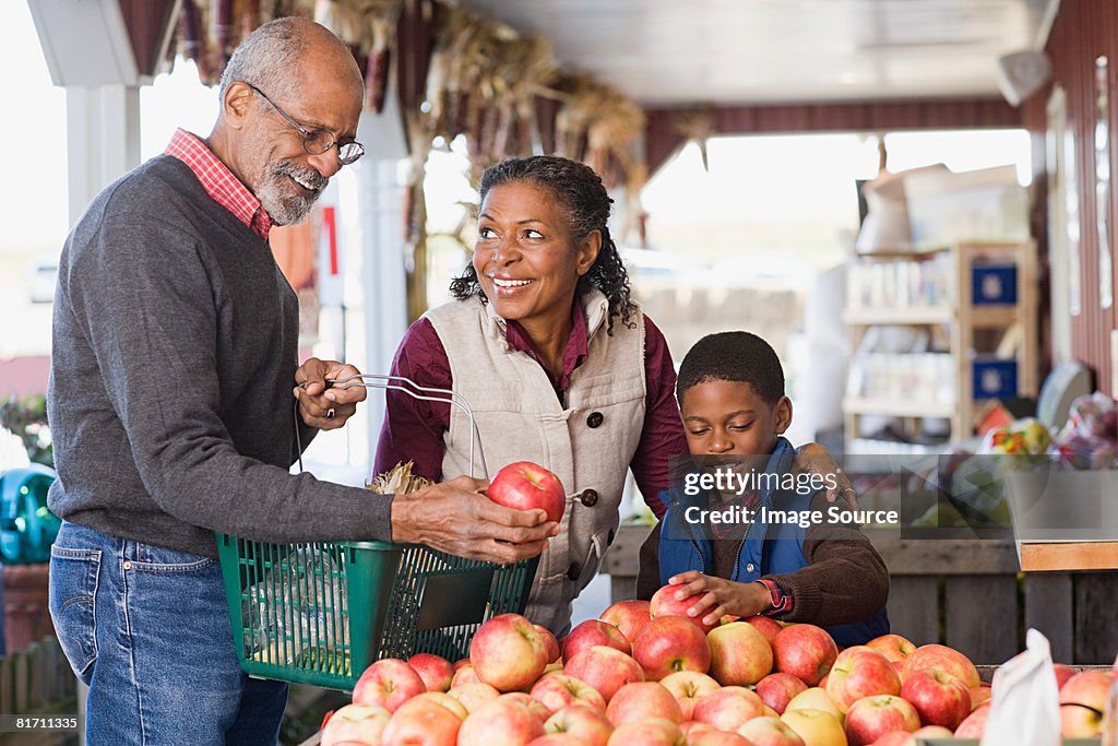 Abuelos y nieto elegir manzanas su