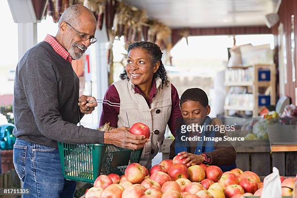 grandparents and their grandson choosing apples - choosing stock pictures, royalty-free photos & images