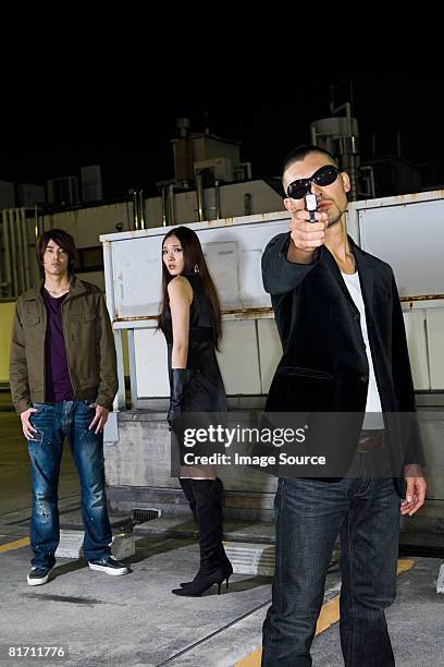 young man aiming a gun at camera - japanese mafia stock pictures, royalty-free photos & images