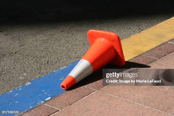 fallen traffic cone on street - verkehrshütchen stock-fotos und bilder