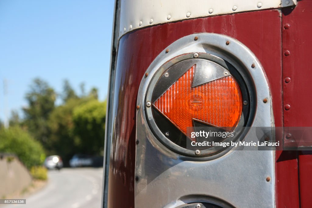 Left arrow-shaped tail light signal of red bus