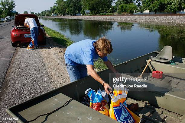 Kenny Lesley and Becky Staten load groceries from their car into the boat as they restock their home that is surrounded by the flooding Mississippi...