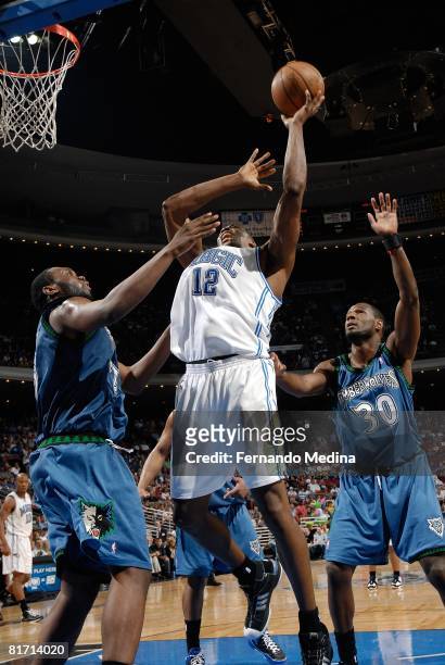 Dwight Howard of the Orlando Magic puts up a shot under pressure against Al Jefferson and Kirk Snyder of the Minnesota Timberwolves during the game...