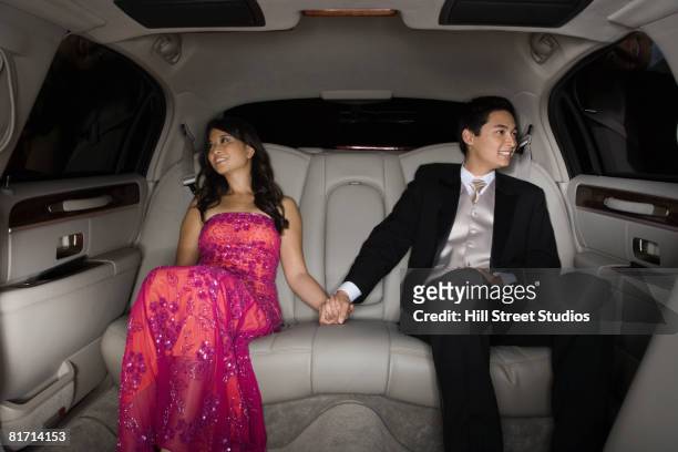 multi-ethnic couple holding hands in limousine - prom limousine stock pictures, royalty-free photos & images