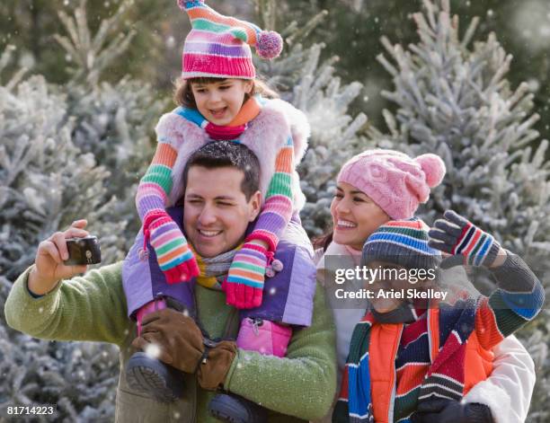 hispanic family taking own photograph in snow - father and mother with their daughter playing in the snow stock pictures, royalty-free photos & images