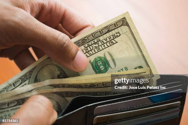 mixed race man taking money out of wallet - billet de 100 dollars américains photos et images de collection