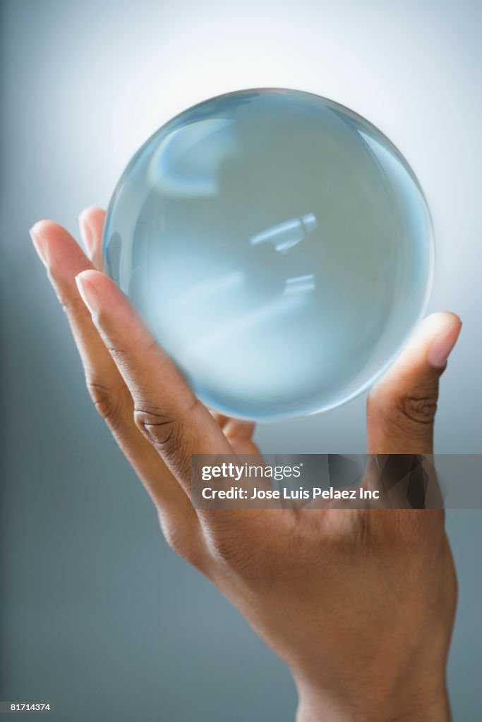 Mixed Race man holding glass orb