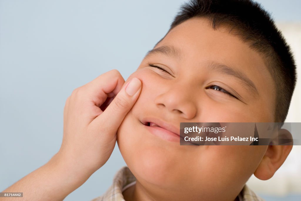 Hispanic boy having cheek pinched