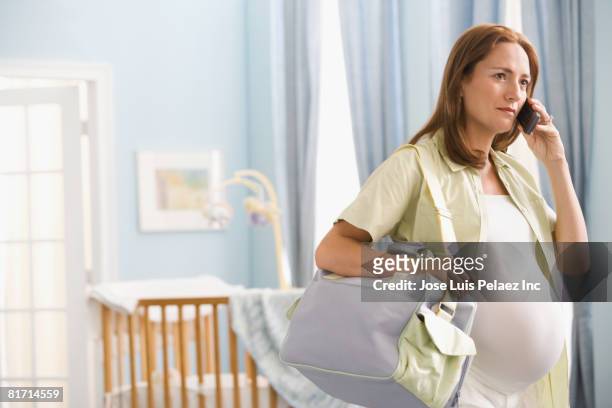 pregnant hispanic woman talking on cell phone - diaper bag 個照片及圖片檔