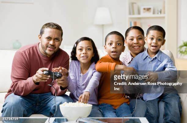 mixed race family playing video games - arab watching tv stock-fotos und bilder