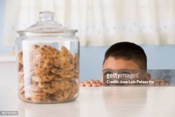 hispanic boy looking at cookies - cookie jar stock pictures, royalty-free photos & images
