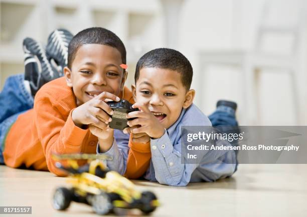 mixed race brothers playing with remote control car - remote control car games stockfoto's en -beelden