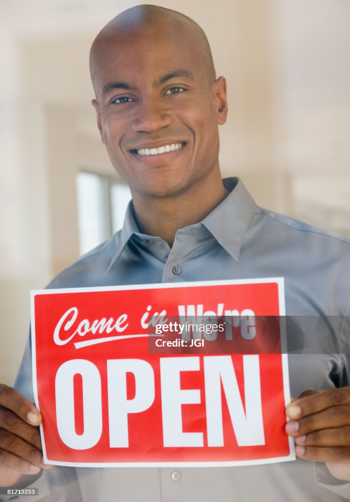 African man holding Open sign