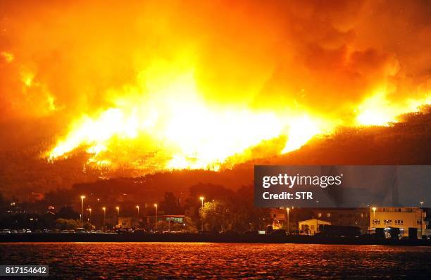 Smoke and flames rise from a fire in the village of Podstrana, near the Adriatic coastal town of Split, early on July 18, 2017. - Montenegro asked on...