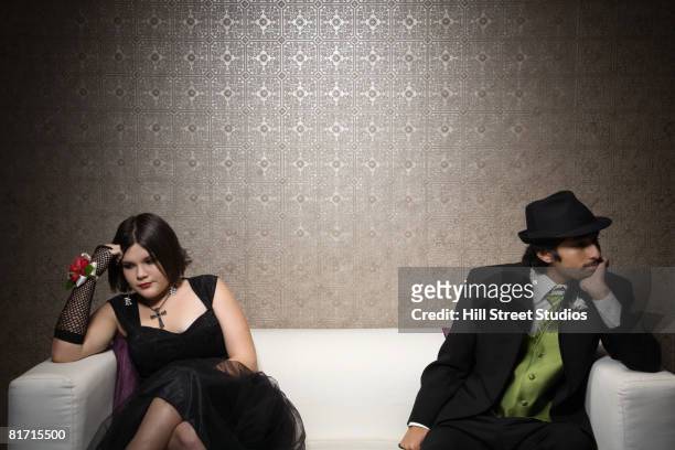 multi-ethnic teenaged couple sitting on sofa - goth boy stock-fotos und bilder