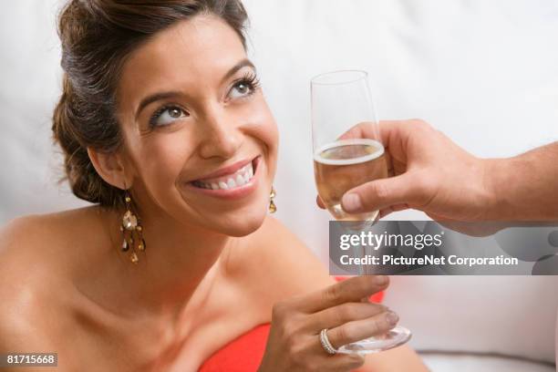hispanic woman accepting glass of champagne - verführung stock-fotos und bilder