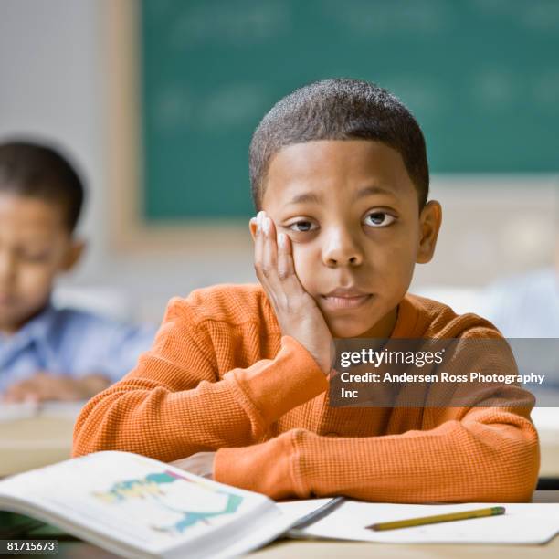 mixed race boy sitting at school desk - écolier-garçon photos et images de collection