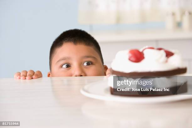 hispanic boy looking at cake - temptation stock pictures, royalty-free photos & images